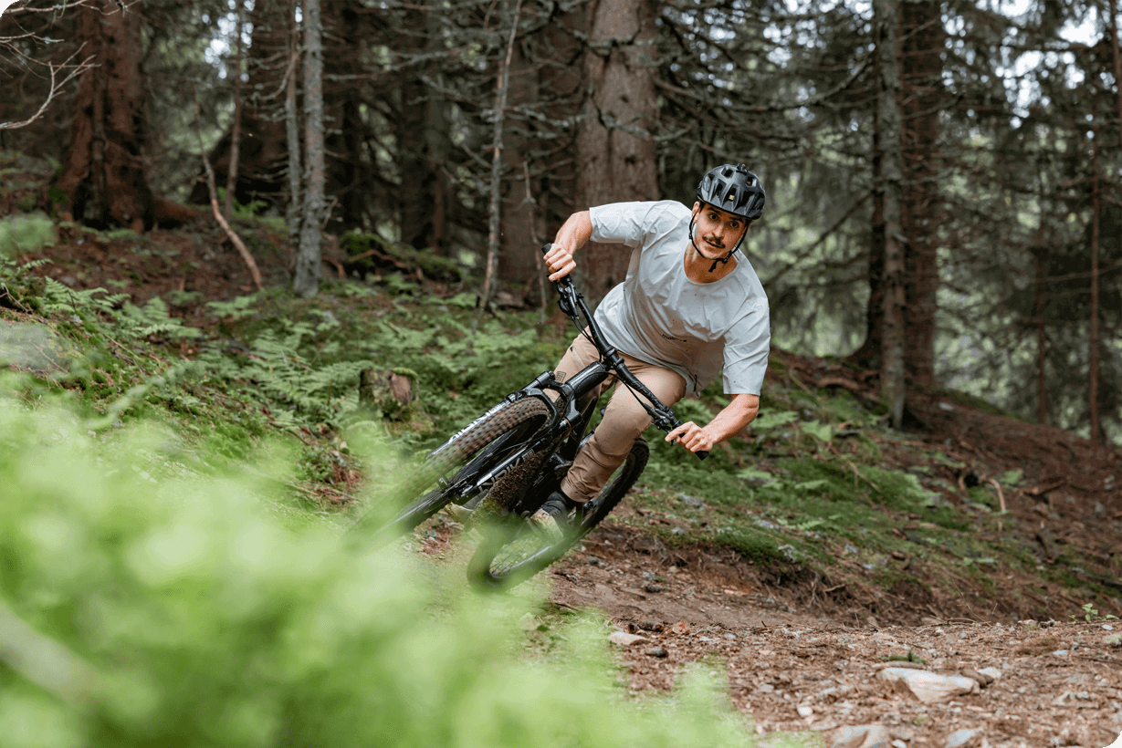 Ciclista montando la bicicleta en un sendero boscoso, disfrutando de la aventura al aire libre.
