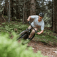 Ciclista montando la bicicleta en un sendero boscoso, disfrutando de la aventura al aire libre.